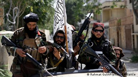 Taliban-Kämpfer mit Waffen und ihrer Flagge in Kabul