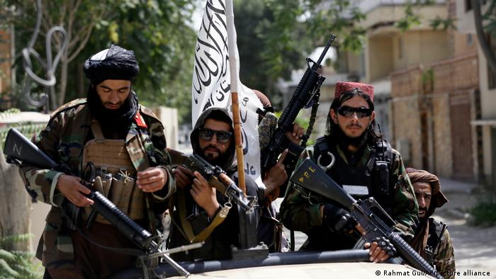 Taliban fighters brandishing weapons display their flag while on patrol in Kabul Thursday