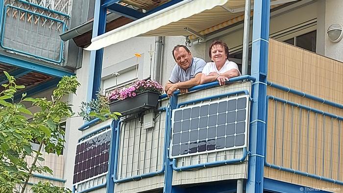 A couple looks over a balcony where a mini solar panel system has been installed