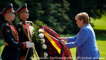German Chancellor Angela Merkel, right, attends a wreath laying ceremony at the Tomb of Unknown Soldier in Moscow, Russia, Friday, Aug. 20, 2021, prior to talks with Russian President Vladimir Putin. The talks between Merkel and Putin are expected to focus on Afghanistan, the Ukrainian crisis and the situation in Belarus among other issues. (AP Photo/Alexander Zemlianichenko, Pool)