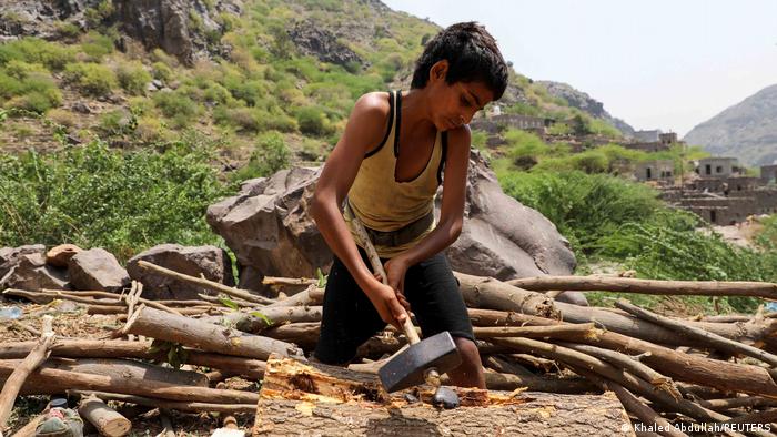 12-летний мальчик разделывает древесину