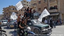 Members of Syria's top jihadist group the Hayat Tahrir al-Sham (HTS) alliance, led by al-Qaeda's former Syria affiliate, parade with their flags and those of the Taliban's declared Islamic Emirate of Afghanistan through the rebel-held northwestern city of Idlib on August 20, 2021. - The armed group that formally broke ties with al-Qaeda years ago is considered to be the most prominent jihadist group in Syria after a decade of war. HTS controls nearly half of the Idlib region -- the last remaining opposition bastion in Syria -- alongside other less influential groups. (Photo by OMAR HAJ KADOUR / AFP) (Photo by OMAR HAJ KADOUR/AFP via Getty Images)