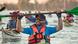 Kayaks in background, man in foreground with beard, ball cap and sunglasses hoists oar Kayaks in background, man in foreground with beard, ball cap and sunglasses hoists oar