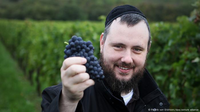 Ein Rabbiner hält Trauben in der Hand. 