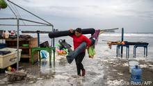 A woman removes umbrellas from the beach as strong waves reach the coast due to Hurricane Grace, which has reached category 2, in Boca del Rio, Veracruz, Mexico, on August 20, 2021. - Grace regained hurricane strength Friday as it barreled towards Mexico for a second time, triggering warnings of flooding and mudslides in mountains on the eastern mainland. (Photo by VICTORIA RAZO / AFP)