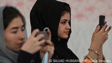 Afghan women use their mobile phones to take pictures of a gathering at a hall in Kabul on August 2, 2021 against the claimed human rights violations on women by the Taliban regime in Afghanistan. (Photo by SAJJAD HUSSAIN / AFP) (Photo by SAJJAD HUSSAIN/AFP via Getty Images)