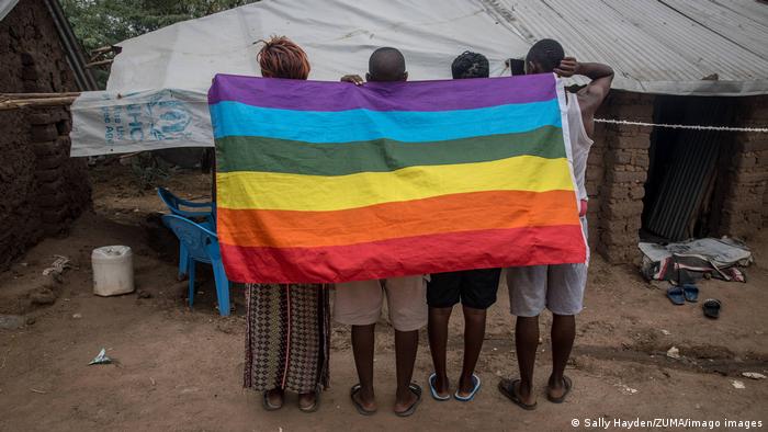 A group of people behind a rainbow flag at a refugee campt in Kenya