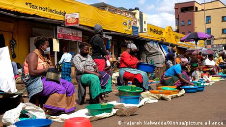Vendors wearing face masks sell vegetables at a market in Kampala, Uganda