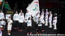 24.08.2021, Japan, Tokio: Paralympics: Eröffnungsfeier im Olympiastadion. Das Refugee Team kommt zu der Eröffnungsfeier ins Olympiastadion. Die Fahnenträger des Teams Alia Issa, Leichtathletik, und Abbas Karimi, Schwimmen, tragen die deutsche Fahne. Foto: Marcus Brandt/dpa +++ dpa-Bildfunk +++