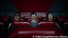 In this Oct. 11, 2019 photo, people watch a 3D movie part of the Iron Man Experience at Hong Kong Disneyland in Hong Kong. The body-blow of months of political protests on Hong Kong’s tourism is verging on catastrophic for one of the world’s great destinations. Geared up to receive 65 million travelers a year, the city’s hotels, retailers, restaurants and other travel-oriented industries are suffering. But some intrepid visitors came specifically to see the protests and are reveling in deep discounts and unusually short lines at tourist hotspots.(AP Photo/Felipe Dana)