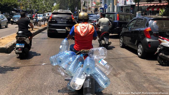Homme sur un scooter avec des bouteilles d'eau vides 