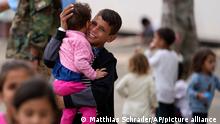 An evacuated young Afghan boy carries a child at the Ramstein US Air Base, Germany