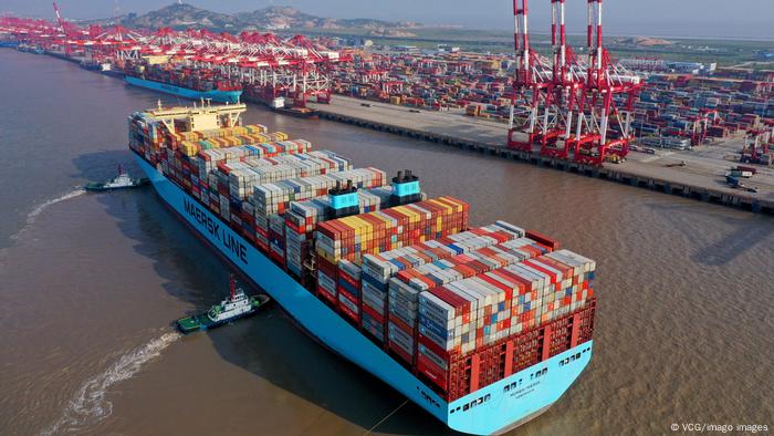 Containerhafen Yangshan in China Shanghai. Ein großes Containerschiff wird von Schleppern in Richtung des Anlegekais geschoben. 