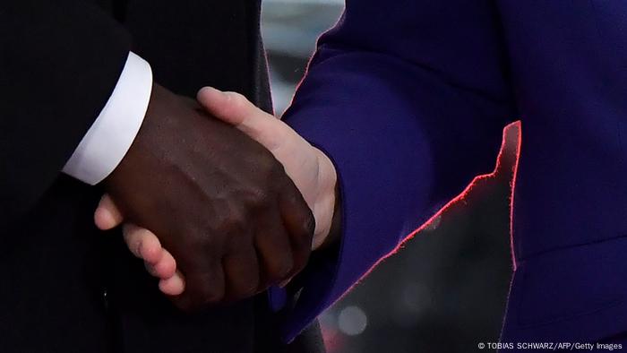 Angela Merkel shakes the hand of AU chief Moussa Faki.