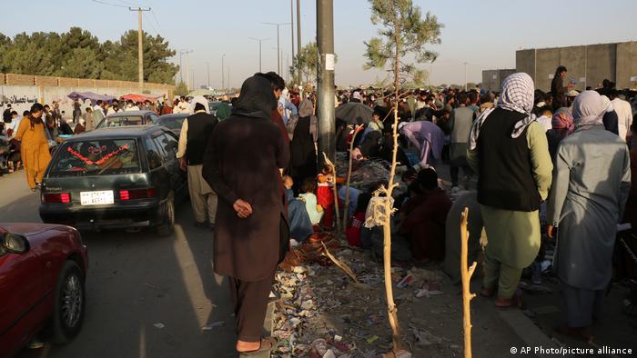 Hundreds of people gather near an evacuation control checkpoint during ongoing evacuations at Hamid Karzai International Airport