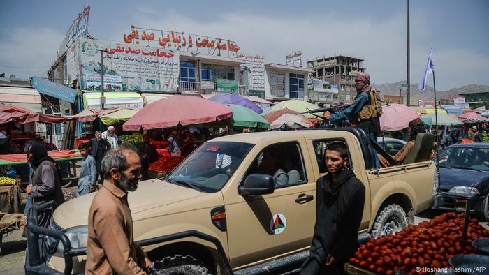 Taliban fighters on a pick-up truck move around a market area, flocked with local Afghan people at the Kote Sangi area of Kabul on August 17, 2021.