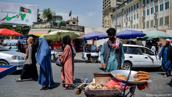 Des Afghanes vêtues de burqa font leurs courses dans un marché à Kaboul le 23 août 2021.