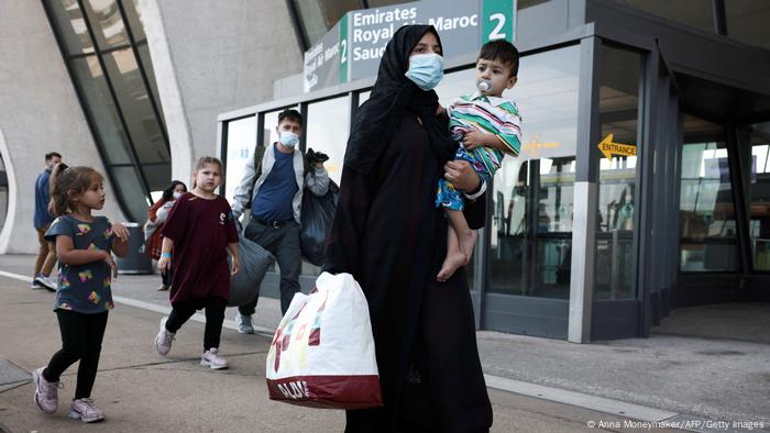 A family evacuated from Kabul Afghanistan walks through the arrival terminal Dulles International Airport to board a bus that will take them to a refugee processing center on August 25, 2021 in Dulles, Virginia.