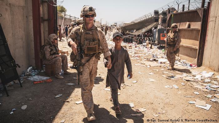 A U.S. Marine with the Special Purpose Marine Air-Ground Task Force-Crisis Response-Central Command (SPMAGTF-CR-CC) escorts a child to his family during an evacuation at Hamid Karzai International Airport in Kabul, Afghanistan, August 24, 2021.