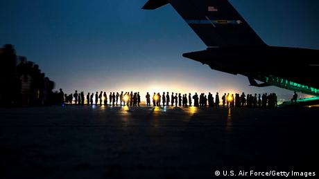 Un avión en Kabul y una larga fila de personas esperando ser evacuadas, en agosto de 2021.