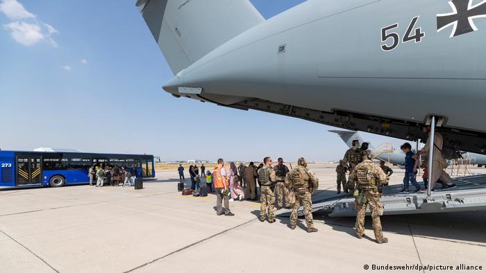 German troops stand on the runway in Tashkent as people disembark from a military plane