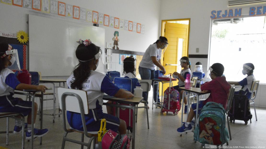 Crianças e professora com proteção facial contra o coronavírus em sala de aula