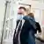 Foto mostra Heinz-Christian Strache, de terno escuro e usando máscara. Ele coça a cabeça enquanto caminha. 
