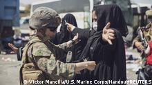 A U.S. Marine checks a woman as she goes through the Evacuation Control Center (ECC) during an evacuation at Hamid Karzai International Airport, Kabul, Afghanistan, August 28, 2021. U.S. Marine Corps/Staff Sgt. Victor Mancilla/Handout via REUTERS. THIS IMAGE HAS BEEN SUPPLIED BY A THIRD PARTY.