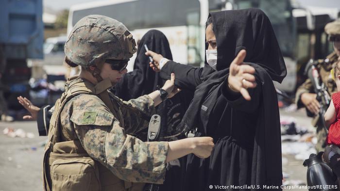 Foto de una persona estadounidense que revisa a otra afgana en el aeropuerto de Kabul.