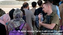 In this image provided by the U.S. Air Force, a U.S. Air Force Airman guides evacuees aboard a U.S. Air Force C-17 Globemaster III at Hamid Karzai International Airport in Kabul, Afghanistan, Tuesday, Aug. 24, 2021. (Senior Airman Taylor Crul/U.S. Air Force via AP)