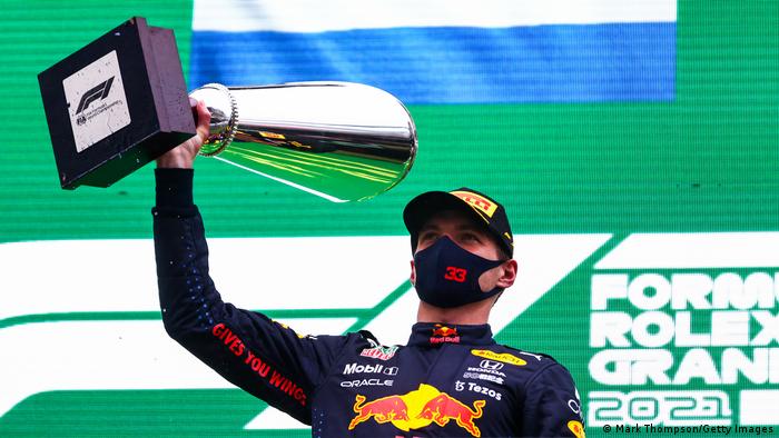 Max Verstappen lifts the Spa trophy in the air.