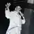 Till Lindemann mit Mikrofon im weißen Nietenanzug auf der Bühne