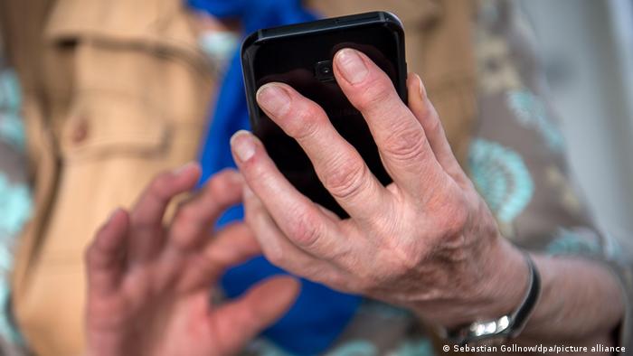 Възрастна жена държи мобилен телефон в ръцете си