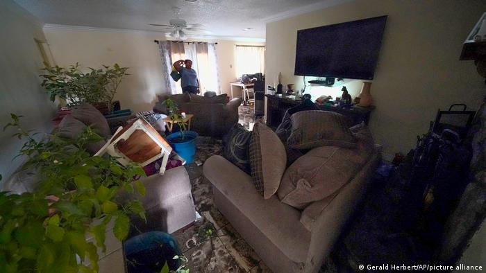 A woman stands in her destroyed living room