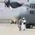 Taliban walk in front of a military airplane 