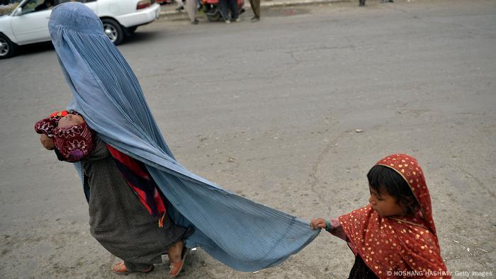 Una mujer con burka, con su hija y un bebé en brazos.