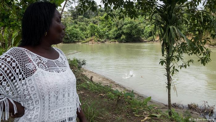 Una mujer de pie mirando al agua del río.