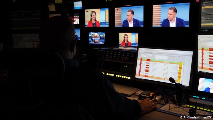 A studio technician works at DW in Berlin, monitoring and helping broadcast Chrupalla's interview on a series of screens. 