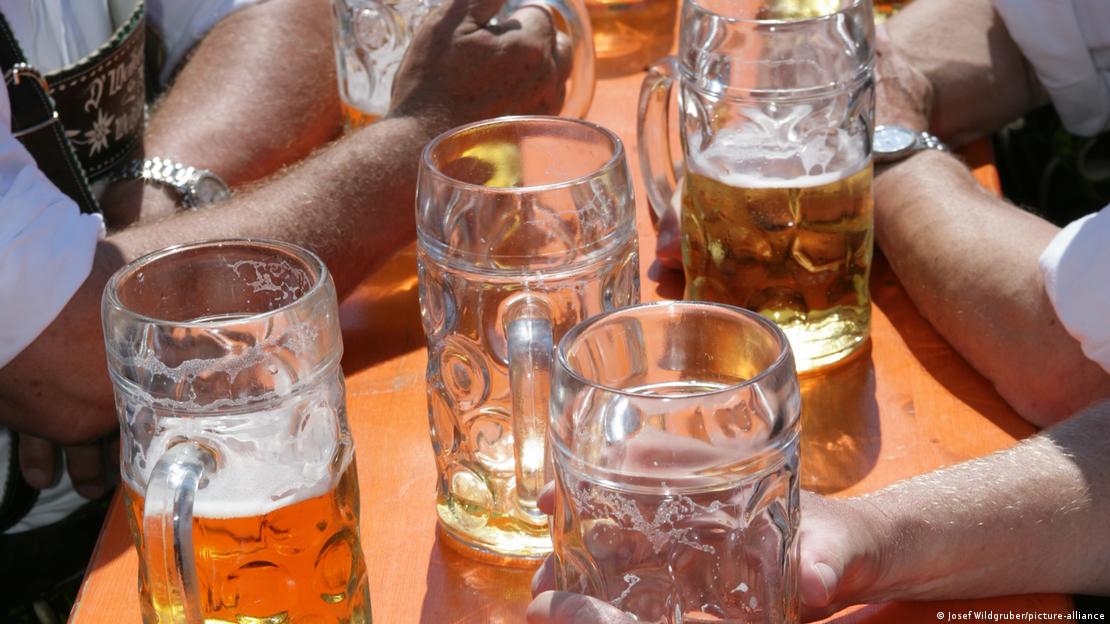 Cerveja em canecos sobre mesa com pessoas.