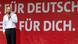 SPD-Kanzlerkandidat Olaf Scholz steht in einem weißen Hemd vor einem roten Plakat, auf dem in großen weißen Buchstaben "Für Deutschland, für Dich" steht. Er hält ein Mikrofon in der Hand und spricht.