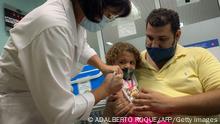 TOPSHOT - Pedro Montano holds his daughter Roxana Montano, 3, while she is being vaccinated against COVID-19 with Cuban vaccine Soberana Plus, on August 24, 2021 at Juan Manuel Marquez hospital in Havana, as part of the vaccine study in children and adolescents. (Photo by ADALBERTO ROQUE / AFP) (Photo by ADALBERTO ROQUE/AFP via Getty Images)