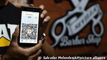 A Barber Shop worker shows his shop's unique QR code for Bitcoin payments, from the BitCoin Beach App, in Santa Tecla, El Salvador, Saturday, Sept. 4, 2021. El Salvador is adopting Bitcoin as an official currency on Tuesday, Sept. 7, 2021. (AP Photo/Salvador Melendez)