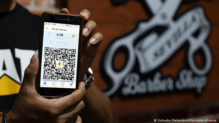 Foto de una persona que muestra la pantalla de un smartphone con un código QR para el uso del bítcoin en El Salvador.