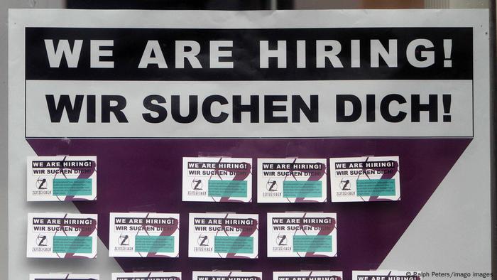 Poster with inscription we are hiring, we are looking for you hangs in the window of an employment agency in Germany