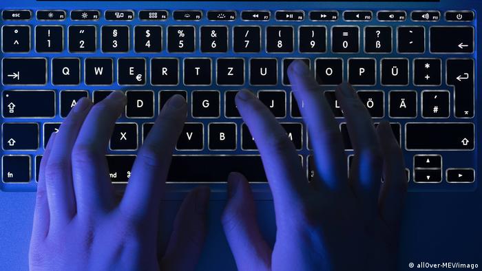 Símbolo de la web oscura: dos manos teclean sobre una computadora en la oscuridad.