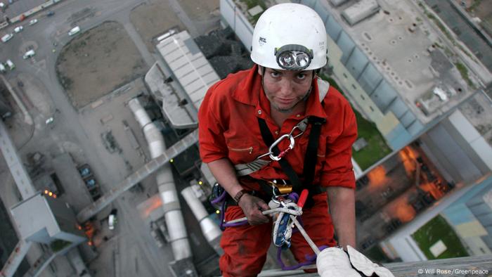 An activist climbs to the top of the chimney of a coal power plant