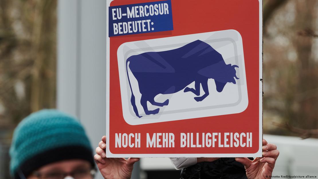 Um cartaz é segurado por um manifestante durante um protesto em frente à embaixada brasileira em Berlim. Em alemão, o cartaz diz 