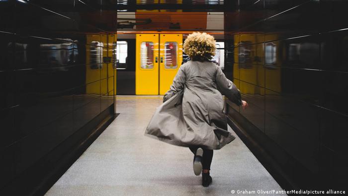 Frau mit wehendem Mantel läuft zur U-Bahn 