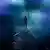 Während der Eröffnungszeremonie läuft ein Fackelläufer, in blau-lilanes Licht und Nebel gehüllt, über seichtes Wasser (Foto: AP)