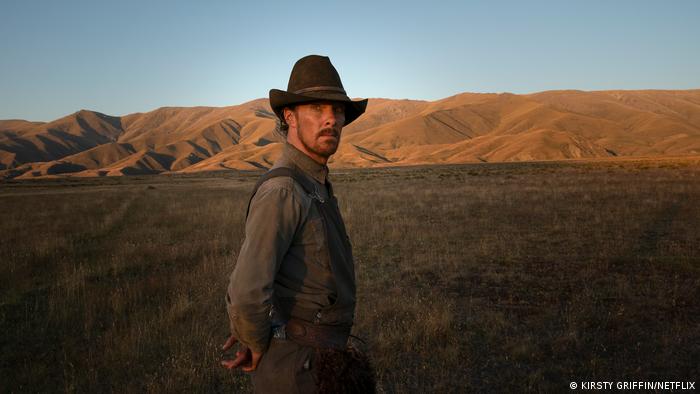 Benedict Cumberbatch in a cowboy hat standing on the plains of Montana with mountains in the background